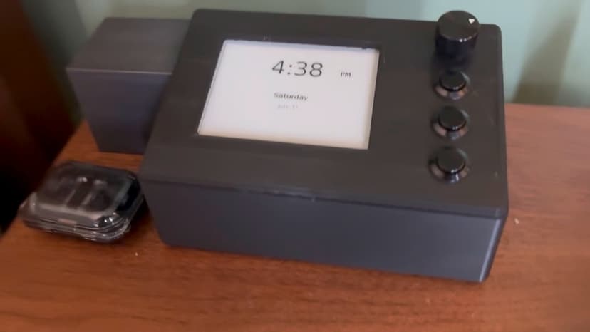 The bedside audio player on a nightstand, showing the time on its e-ink display